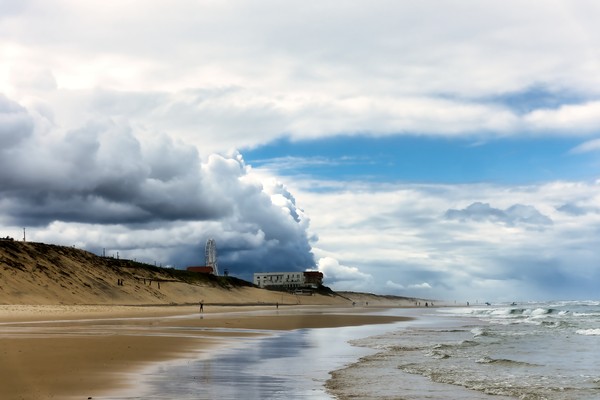 Plan d’une large plage avec des nuages se reflétant dans l’eau et le ciel bleu
