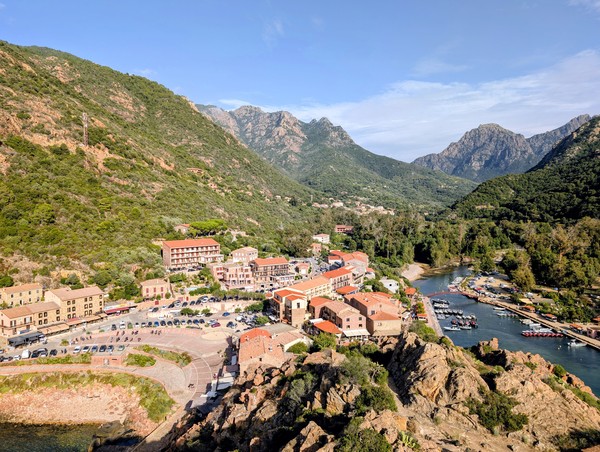 Vue sur la petite ville de Porto Ota et le port de plaisance avec les hautes montagnes en arrière-plan avec soleil et ciel bleu